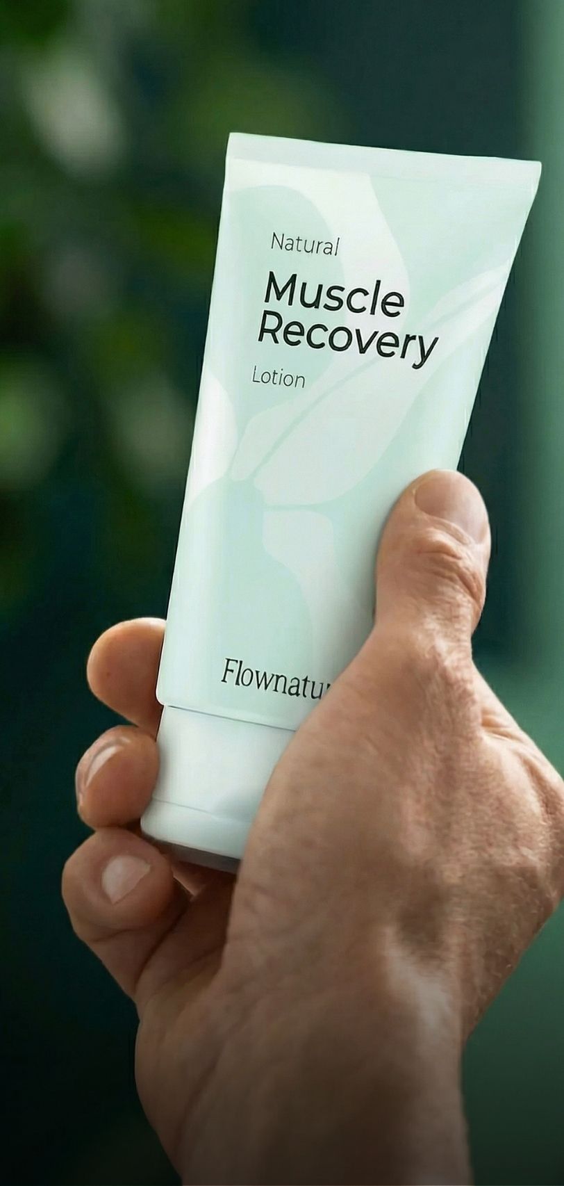 A hand holding a tube of Flownatura Natural Muscle Recovery Lotion.
