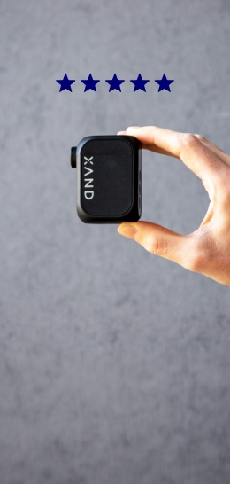 A hand holding a black XAND device with five stars above it.