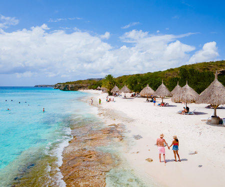 <p>koppel loopt over het strand van Curacao in de meivakantie</p>