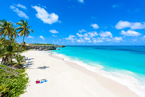 Tropisch strand op Barbados met een handdoekje op het zand en palmbomen op de achtergrond