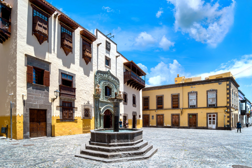 Binnenplaats van Casa de Colón in Las Palmas met historische gebouwen, een stenen fontein en geplaveide bestrating.