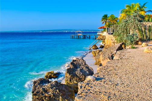 Bachelor Beach op Bonaire met helder turquoise zeewater, een smalle strook zand en rotsen langs de rustige kust