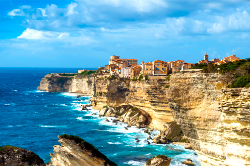 Bonifacio op Corsica met historische bebouwing boven op hoge witte kalkstenen kliffen en helderblauw zeewater langs de kust.