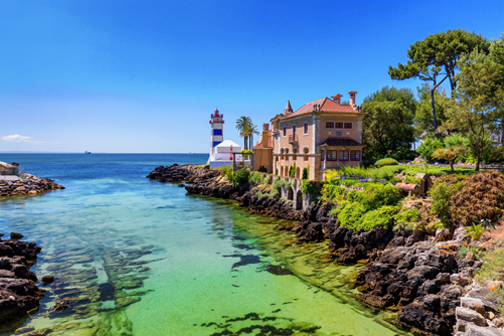 Cascais in Portugal met zandstrand, helderblauw water en witte gebouwen langs de kust onder een zonnige lucht.