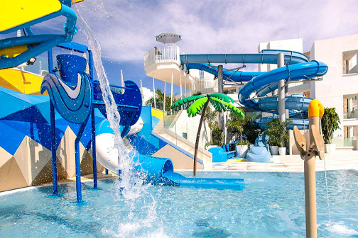 Waterspeeltuin met blauwe glijbanen, fonteinen en ondiep zwembad bij Servatur Puerto Azul, geschikt voor jongere kinderen.