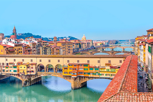 Uitzicht op Florence met terracotta daken, de Duomo met grote koepel en historische gebouwen langs de rivier onder een heldere lucht.
