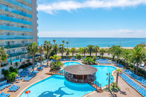 Ronde bar midden in het zwembad met loopbruggetjes omringd door ligbedden en dichtbij zee