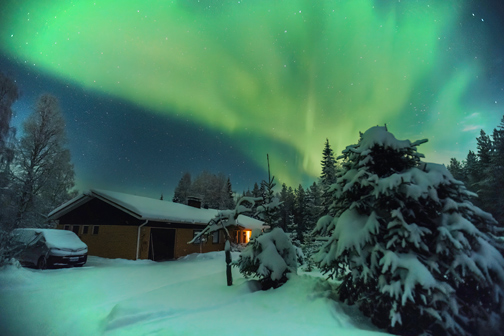 Noorderlicht boven besneeuwd huis in bos in Rovaniemi, Lapland en Finland