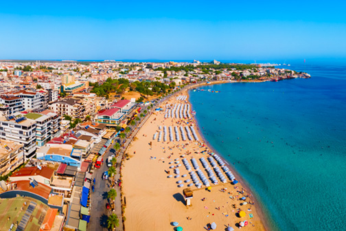 Strand van Didim, Altikunkum Beach, van bovenaf met gouden strand, strandbedjes, en Didim op de achtergrond