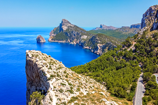 Cap de Formentor op Mallorca met steile rotskliffen, helderblauwe zee en een kronkelende kustlijn omringd door groen.