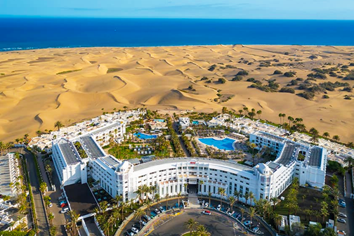 Luchtfoto van RIU Palace Maspalomas met zwembaden, tropische tuinen en directe ligging naast de beroemde duinen van Maspalomas.