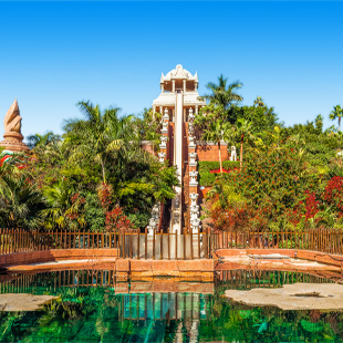 Siam Park op Tenerife met tropisch waterpark, hoge glijbanen, palmbomen en zwembaden onder een heldere blauwe lucht.