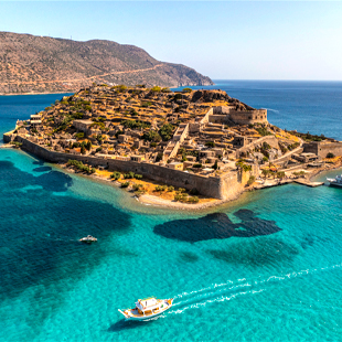 Spinalonga bij Kreta met historische stenen vestingwerken op het eiland, omringd door het helderblauwe water van de Middellandse Zee.