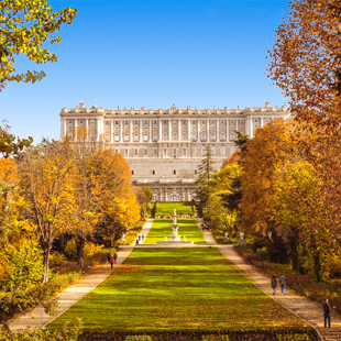 Uitzicht op Madrid met het Koninklijk Paleis, brede straten en historische gebouwen onder een heldere blauwe lucht.