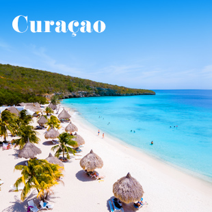 Wit zandstrand op Curaçao met palmbomen, rieten parasols en strandgangers langs een helderblauwe zee onder een zonnige hemel.